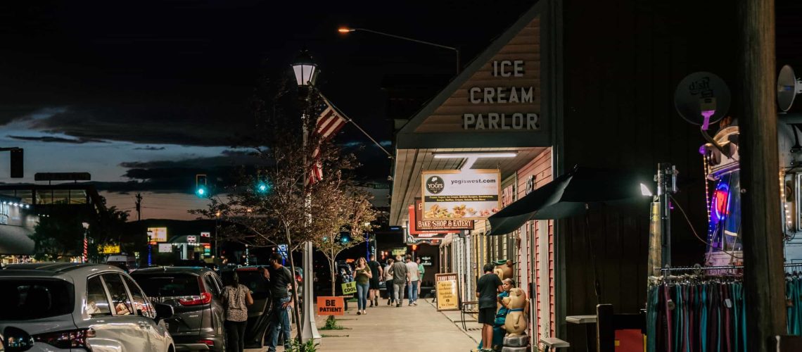 Night view of Westgate Theatre with people and parked cars.